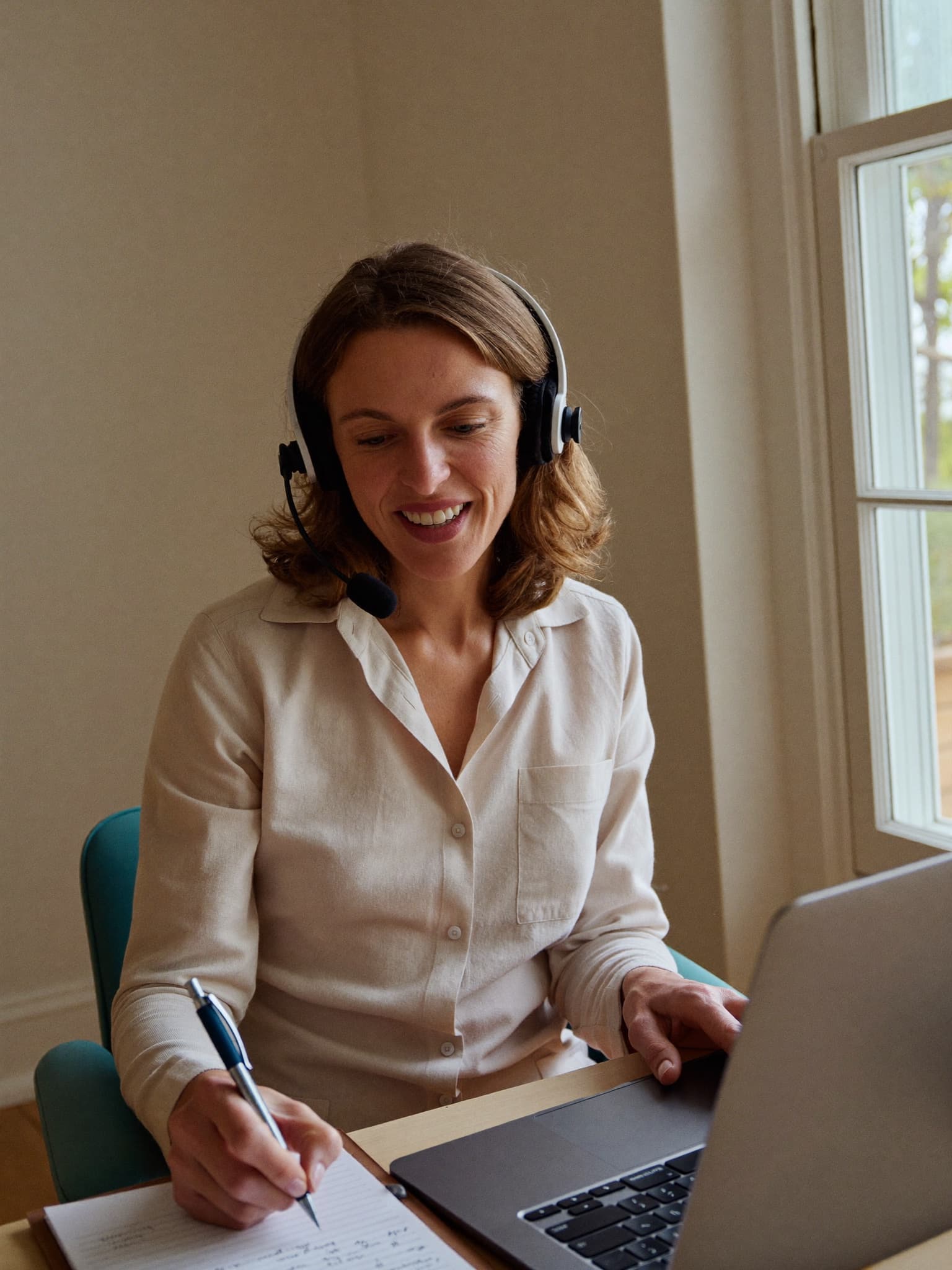 Pflegelotsin mit Headset berät eine Familie freundlich am Telefon